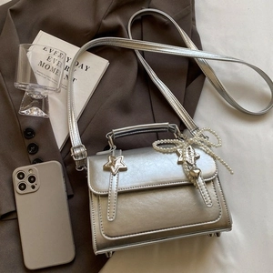 Sac bandoulière argenté avec nœud en perles et clous étoiles sur fond élégant