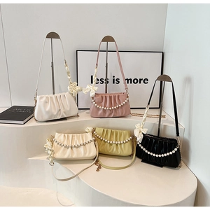Multiple pleated shoulder bags in soft colors with pearl chains and ribbon charms