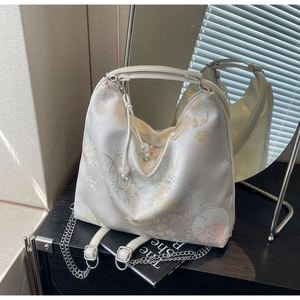 Detailed embroidery of floral and cloud patterns on a satin bag with pearl drawstring