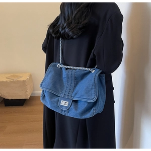 Detail of washed denim shoulder bag with silver chain strap shown on a model