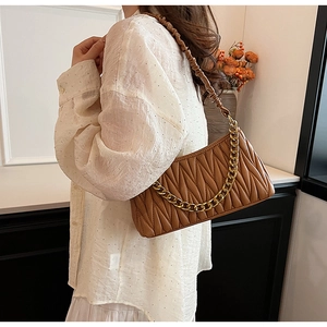 Détails de la texture en cuir plissé caramel et chaîne dorée du sac à bandoulière
