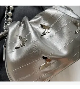 Detail of silver embossed bucket bag with metallic butterfly and beaded chain strap