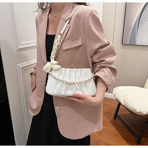 Detail of white pleated shoulder bag featuring elegant pearl chain and satin ribbon strap