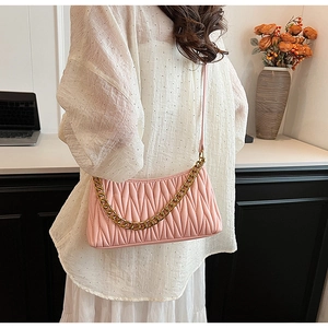 Détail du sac à bandoulière plissé rose avec chaîne dorée et texture matelassée élégante
