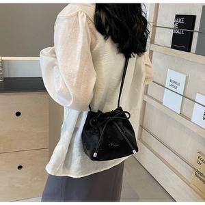 Vue détaillée du sac seau en velours noir avec cordon de serrage et grand nœud sur la bandoulière