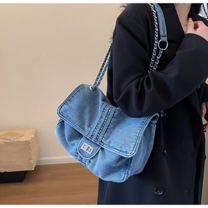 Detail shot of light blue denim shoulder bag featuring a silver chain and twist-lock