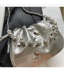 Detail of silver metallic cloud bag with butterfly charms and large beaded top handle