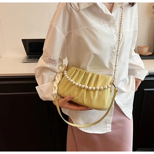 Detail of pleated shoulder bag with pearl strap and scarf handle in a lifestyle setting
