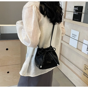 Détail du sac seau noir avec texture dorée vintage et décoration de nœud élégant
