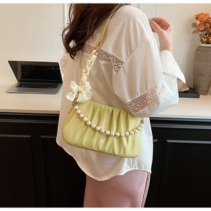 Detail shot of pale yellow pleated shoulder bag with pearl chain and ribbon bow detail
