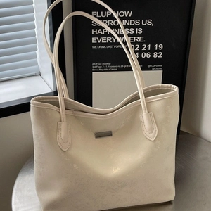 Minimalist beige tote bag in shimmering PU leather with silver plaque on a metal stand