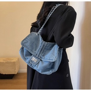 Detailed view of blue denim shoulder bag with silver chain strap and metal turn-lock