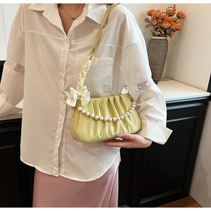 Detail of pleated shoulder bag featuring pearl chain and white satin ribbon bow accent