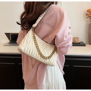Détail d'un sac sous les aisselles plissé beige avec chaîne dorée sur l'épaule