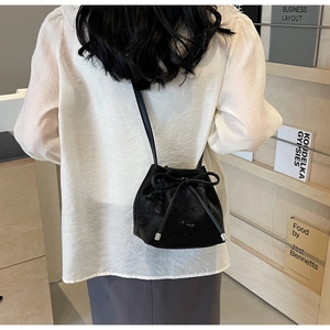 Détail d'un sac seau noir avec cordon de serrage, nœuds décoratifs et embouts argentés