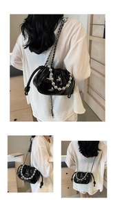 Detail view of black patent leather bag with silver butterfly and beaded handle strap