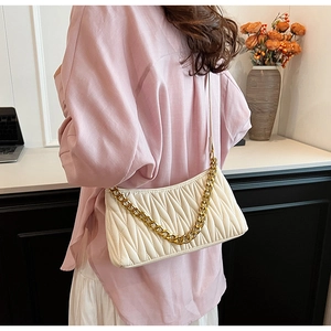 Détail du sac baguette plissé blanc cassé avec une grosse chaîne en métal doré