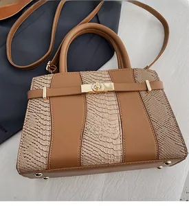 Detail of snake skin texture and golden twist lock on a brown leather Kelly bag