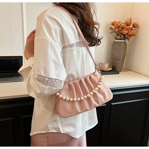 Detail of light pink pleated shoulder bag featuring elegant oversized pearl chain strap