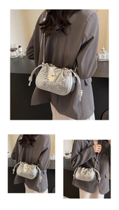Detail of silver metallic bucket bag featuring pleated design and sleek chain strap
