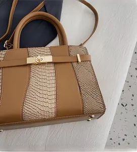 Close-up of caramel faux leather bag with snake pattern and gold twist lock hardware