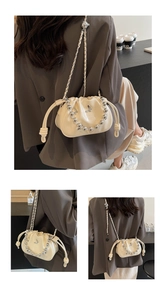 Detail view of cream bucket bag featuring metal butterfly charm and beaded chain strap