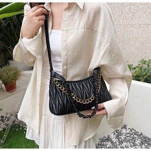 Détail du sac noir plissé matelassé avec chaîne dorée et poignée en cuir froncée