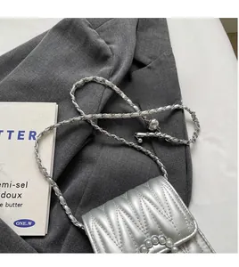 Dettaglio della borsa trapuntata argento con fibbia di perle e tracolla a catena