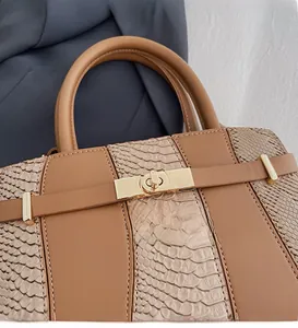 Close-up of golden metal twist lock and snake-embossed leather on brown crossbody bag