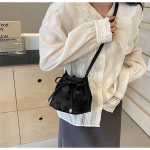 Détail d'un sac seau en cuir noir avec cordon de serrage et accents métalliques argentés