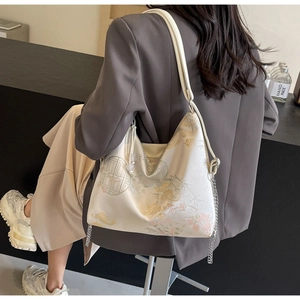 Close-up of beige embroidered floral patterns with golden metallic chain on crossbody bag