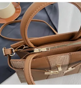 Close-up of golden zipper and snakeskin pattern detail on brown leather tote bag