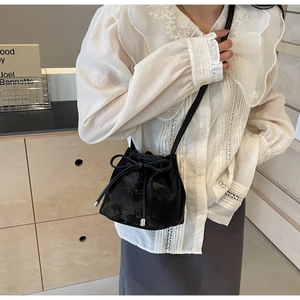 Vue latérale du sac seau noir à cordon avec nœud sur un mannequin en bandoulière