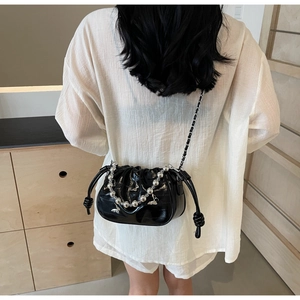 Detail of black glossy cloud bag featuring silver beaded chain and metal butterfly charm