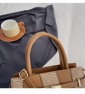 Close-up of warm brown leather tote with snake pattern texture and round top handle