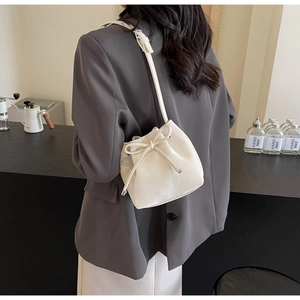 Détail du sac seau en cuir blanc avec nœud de serrage et bandoulière minimaliste
