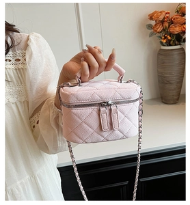 Detail of pink quilted leather mini bag with double zippers and chain strap held by hand