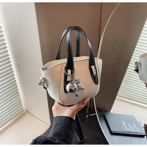 Gros plan d'un sac à main blanc avec poignée noire et pendentif lapin argenté