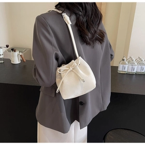 Détail du sac seau blanc crème avec nœud de serrage et fine bandoulière élégante