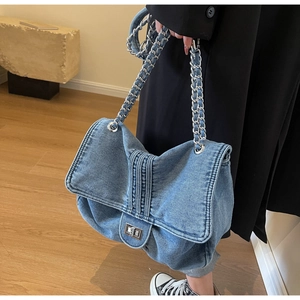 Detail of blue denim shoulder bag with silver chain strap and metal swivel lock closure