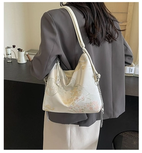 Detail of embroidered floral tote bag with silver chain and pearled drawstring on model