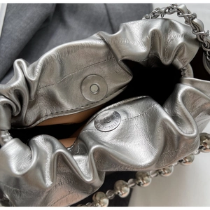 Macro shot of silver textured bucket bag with drawstring closure and beaded chain detail