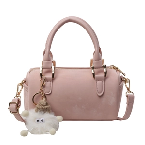 Pink Boston style handbag with adjustable strap and decorative plush charm in front view