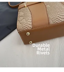Close-up of tote bag base showing gold protective rivets and snake pattern texture