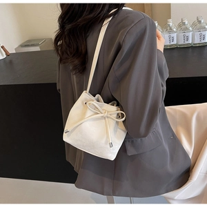 Vue latérale du sac seau en cuir blanc avec cordon à nœud élégant et bandoulière fine