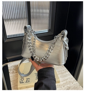 Detail of silver crescent underarm bag with crocodile texture and metallic chain handle