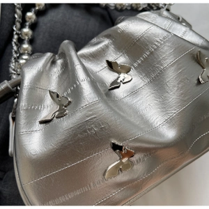 Detail of silver metallic handbag featuring butterfly studs and pearl chain strap