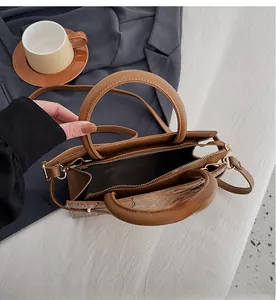 Close-up of caramel crocodile embossed handbag showing zip closure and spacious interior