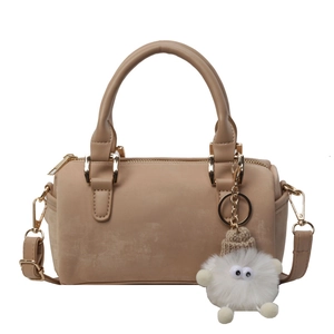 Light brown Boston handbag with dual handles, crossbody strap and a cute plush monster charm
