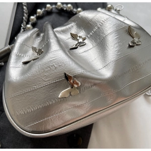 Detail of silver pleated handbag with metallic butterflies and pearl bead chain